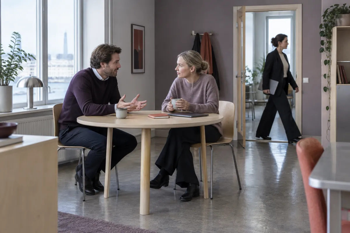 Två kollegor diskuterar planerna vid ett bord i ett ljust kontor