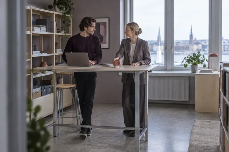 Två kollegor arbetar vid en ståbänk i ett bakre kontor