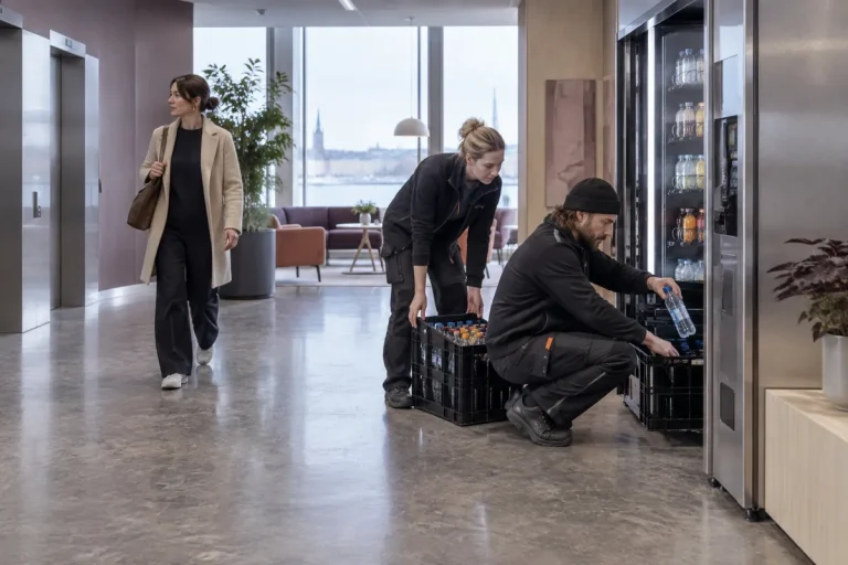 Servicetekniker fyller på en varuautomat i en entré